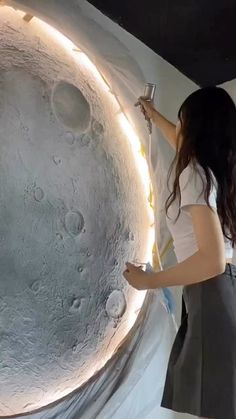 a woman is painting the moon with white paint