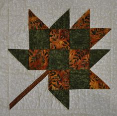 a quilted wall hanging with an orange and green star