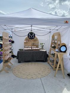 an outdoor market with tables and chairs under a white tent that has a black table cloth on it