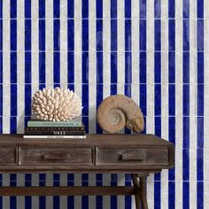 a blue and white striped wallpaper next to a wooden table with books on it