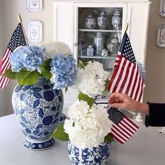 a vase with flowers and american flags in it sitting on a table next to another vase