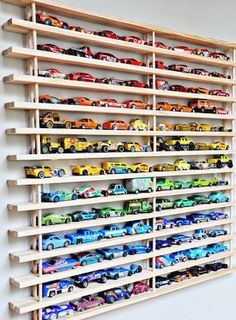 a wooden shelf filled with lots of toy cars on top of it's sides