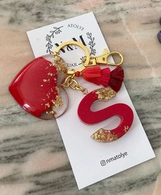 two red and gold earrings on top of a white piece of paper