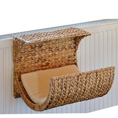 a wicker chair hanging from the side of a wall with a cushion on it