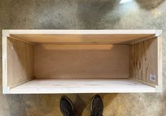 a pair of black shoes standing on top of a wooden shelf next to a wall