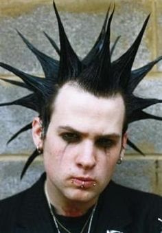 a young man with spiked hair and piercings on his head looking at the camera