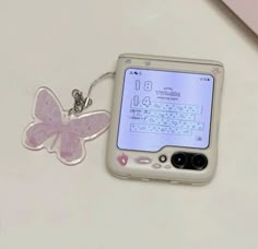 an electronic device with a butterfly keychain attached to it's back end