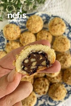 a person is holding a cookie in their hand and some cookies are on the plate behind them