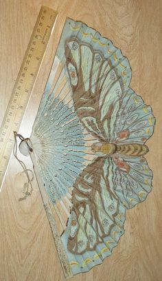 a blue and brown fan sitting on top of a wooden floor next to a ruler