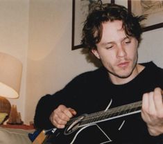 a young man playing an electric guitar in his living room