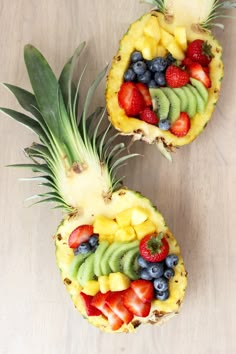 two pineapples decorated with fruit are sitting on a table