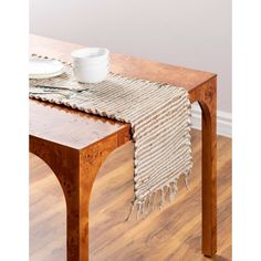 a wooden table topped with a white plate and cup on top of a wooden table