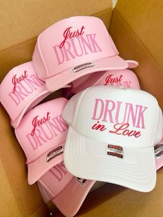 pink hats with just drunk in love written on the front and back are sitting in a cardboard box