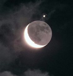 the moon and two stars are visible in the night sky above some dark clouds,