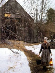 an old woman is standing outside in the snow holding a bucket and looking at something