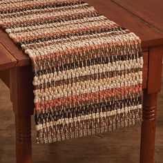 a wooden table topped with a brown and white striped runner next to a wooden table