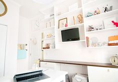 a laptop computer sitting on top of a desk in front of a white book shelf