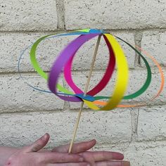 a hand holding a multicolored pinwheel on a stick