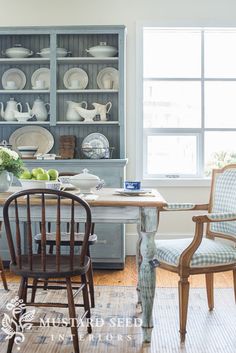 a dining room table and chairs in front of a china cabinet with dishes on it