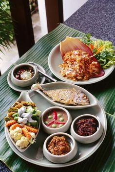 two plates with different foods on them sitting on a table next to each other,