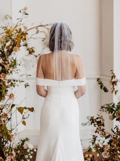 the back of a bride's wedding dress, with her veil draped over her shoulder