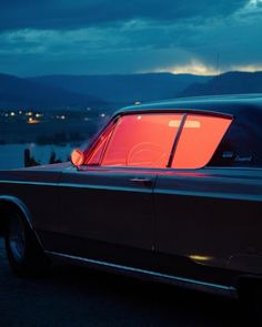 an old car with the sun shining on it's windows at night in front of mountains