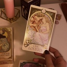 a person holding up a tarot card next to some other items on a table