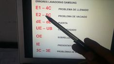 a hand holding a pen in front of a computer screen with spanish words on it