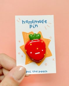 a hand holding a pin with a red apple on it's back and the words, handmade pun put the peach in front