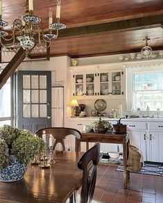 a dining room table and chairs in front of a chandelier hanging from the ceiling