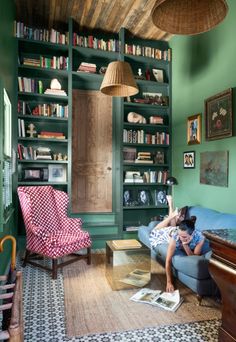 a person sitting on a couch in front of a bookshelf with lots of books