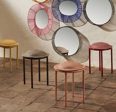 four different colored stools and mirrors on the wall