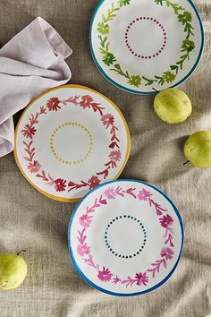 three plates sitting on top of a table next to two pears and one apple