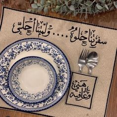 a place mat with arabic writing on it next to a fork, knife and spoon