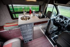 the interior of a camper van with sink and kitchen area in front of it