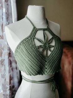 a white mannequin wearing a green crochet halter top