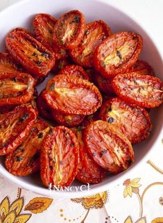 a white bowl filled with sliced tomatoes on top of a table