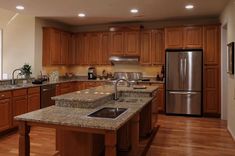 a large kitchen with wooden cabinets and granite counter tops, along with stainless steel appliances