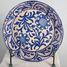 a blue and white plate sitting on top of a table next to a metal stand