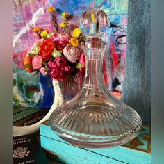 a glass vase with flowers in it sitting on a table next to a passport and a painting