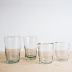 four glasses are lined up on a shelf