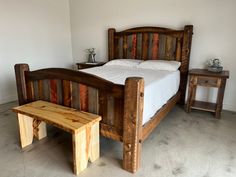 a bed with wooden headboard and foot stools next to it in a room