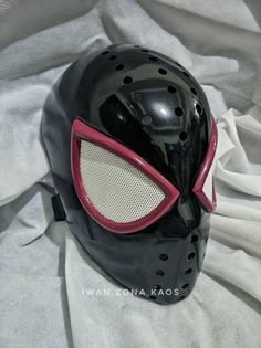 a black mask with red eyes on top of a white sheet