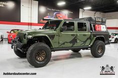 a green jeep is parked in a showroom