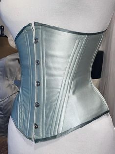 Tosca underbust corset, made in double layered silk satin. This corset is meant to be worn to emphasise the classic hourglass silhouette. Offers up to 10 cm waist reduction.  The undercup shape and hip can be shaped for perfect comfort and fit. Classic metal busk and plastic boning, steel boning available on request, please dm me for more informations. Currently available ready to ship: Sage green double layered silk satin with contrast binding. FULLY CLOSED 64 cm underbust 57 cm waist 78 cm hig Fitted Silk Strapless Corset, Strapless Silk Fitted Corset, Underbust Corset Dress With Boning And Fitted Bodice, Fitted Silk Corset With Boning, Formal Underbust Bodice With Corset Back, Fitted Evening Corset Partially Lined, Elegant Formal Underbust Bodice, Fitted Silk Overbust Corset, Fitted Underbust Corset Belt For Formal Occasions