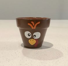 a brown cup with an angry bird painted on it's face sitting on a counter