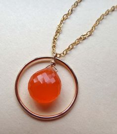 An orange carnelian briolette is suspended within a gold fill circle. The circle hangs from a gold fill chain. The gold fill chain is secured with a gold fill spring ring clasp, gold fill closed ring, and carnelian rondelles. * The AAA, micro faceted heart briolette measures 7/16" long x 3/8" wide. * The 14kt gold fill circle is (3/4"). * The AAA micro faceted carnelian rondelles are 4.5mm (under 3/16"). * All gold fill is 14kt. * From end to end, the length of the necklace is 18 inches. * PLEASE NOTE: PHOTOS ARE DELIBERATELY TAKEN UP CLOSE TO SHOW DETAIL, SO JEWELRY LOOKS LARGER THAN IT REALLY IS. * PLEASE READ THE DESCRIPTION ABOVE CAREFULLY FOR ACTUAL MEASUREMENTS. * Your purchase will come in a jewelry gift box with ribbon. (One jewelry gift box with ribbon per total order.) I ship ord Formal Orange Carnelian Necklace, Orange Carnelian Necklace With Round Pendant, Orange Carnelian Pendant Jewelry, Vintage Orange Carnelian Necklace, Carnelian Orange Amulet Necklace, Jewelry Looks, Gift Box With Ribbon, Box With Ribbon, Necklace Orange