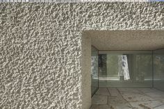 an entrance to a building with glass doors and concrete walls that are covered in small holes