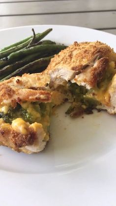 a white plate topped with meat and veggies next to green beans on a table