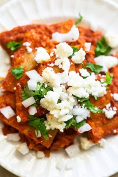 a white plate topped with lasagna covered in feta cheese and parsley